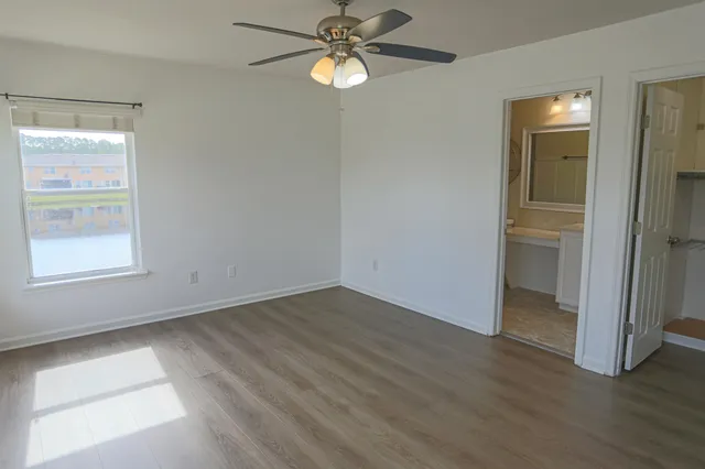 an empty room with wooden floor closet and windows