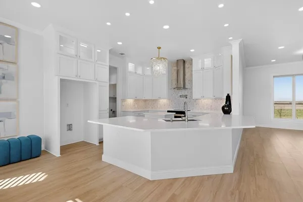 a large white kitchen with kitchen island a sink a stove and a refrigerator