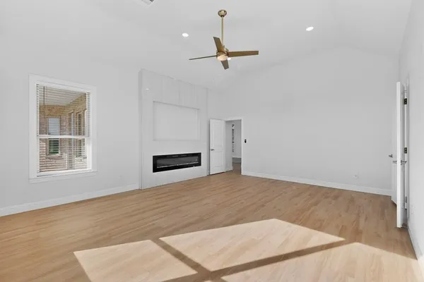 a view of an empty room with a window and kitchen view