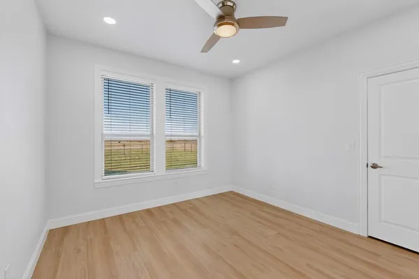 an empty room with wooden floor fan and windows