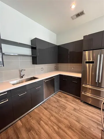 a large kitchen with stainless steel appliances a sink and a refrigerator