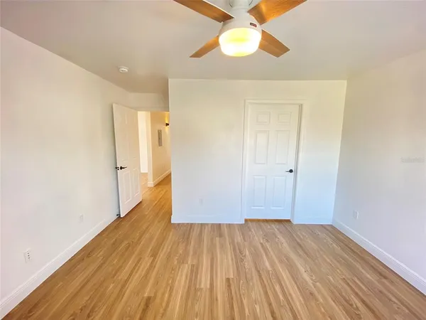 a view of a room with wooden floor and a ceiling fan