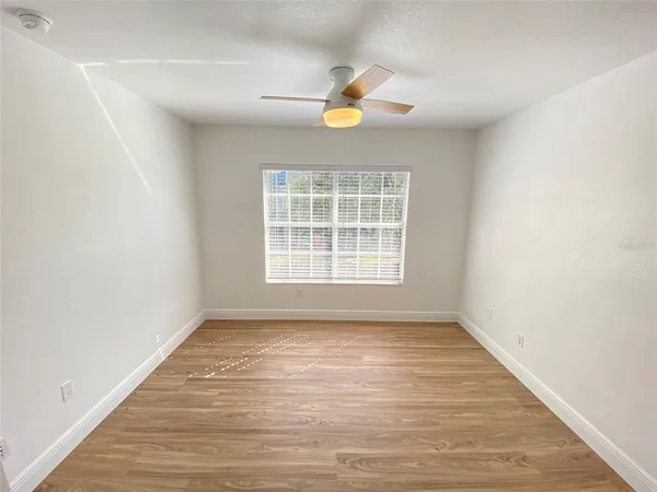 a view of an empty room with wooden floor and a window