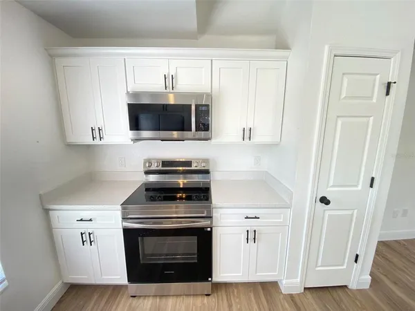 a kitchen with cabinets stainless steel appliances and wooden floor