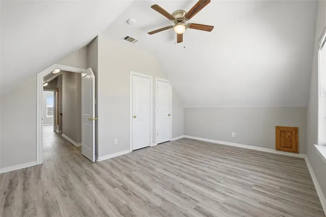 an empty room with wooden floor a ceiling fan and windows