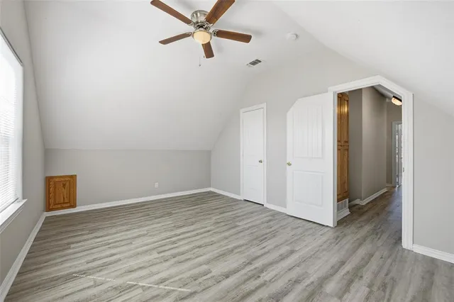 an empty room with wooden floor closet and windows