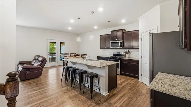a kitchen with stainless steel appliances kitchen island granite countertop a sink refrigerator and cabinets