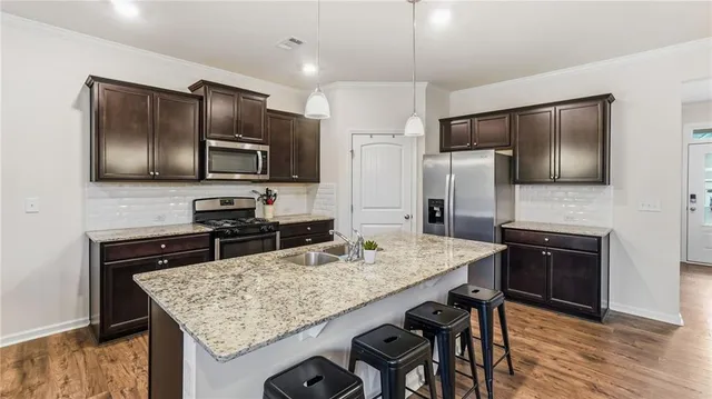 a kitchen with stainless steel appliances wooden floor wooden cabinets and refrigerator