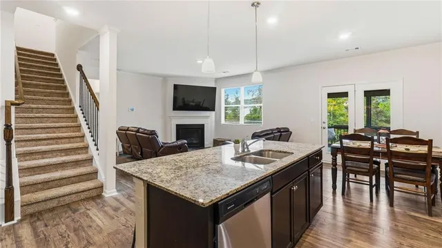 a kitchen with granite countertop kitchen island stainless steel appliances a table chairs sink and stove