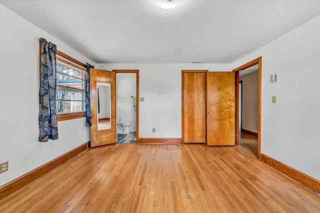 a view of an empty room with window and chandelier fan