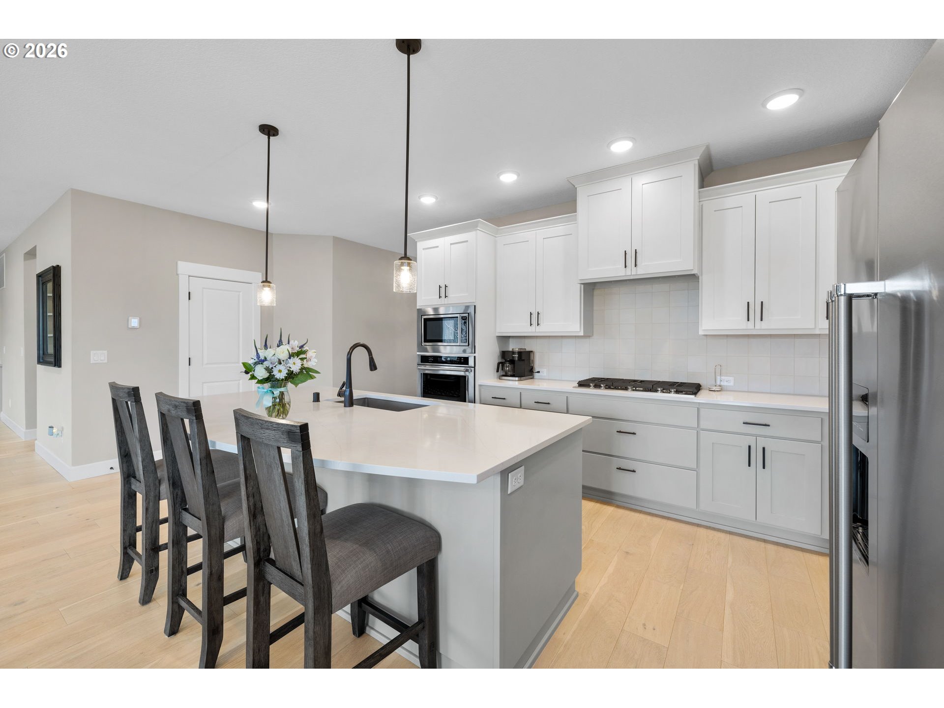 17311 Northeast 28th Court Ridgefield, WA 98642 - Photo 7 of 38 a kitchen with kitchen island a dining table chairs stainless steel appliances and cabinets