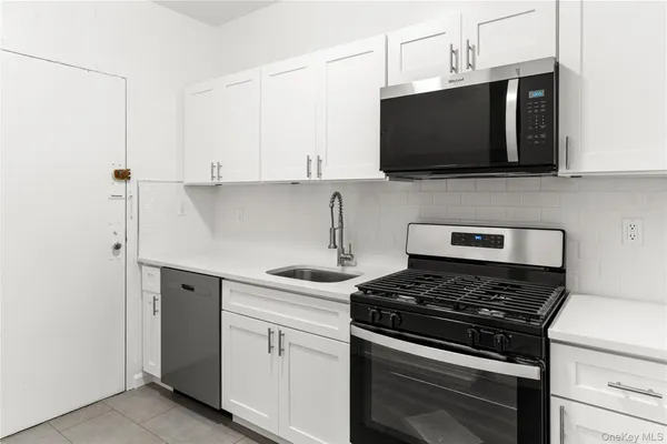 a kitchen with stainless steel appliances a sink dishwasher stove and microwave with wooden floor