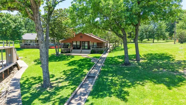 a view of a house with a big yard potted plants and large tree