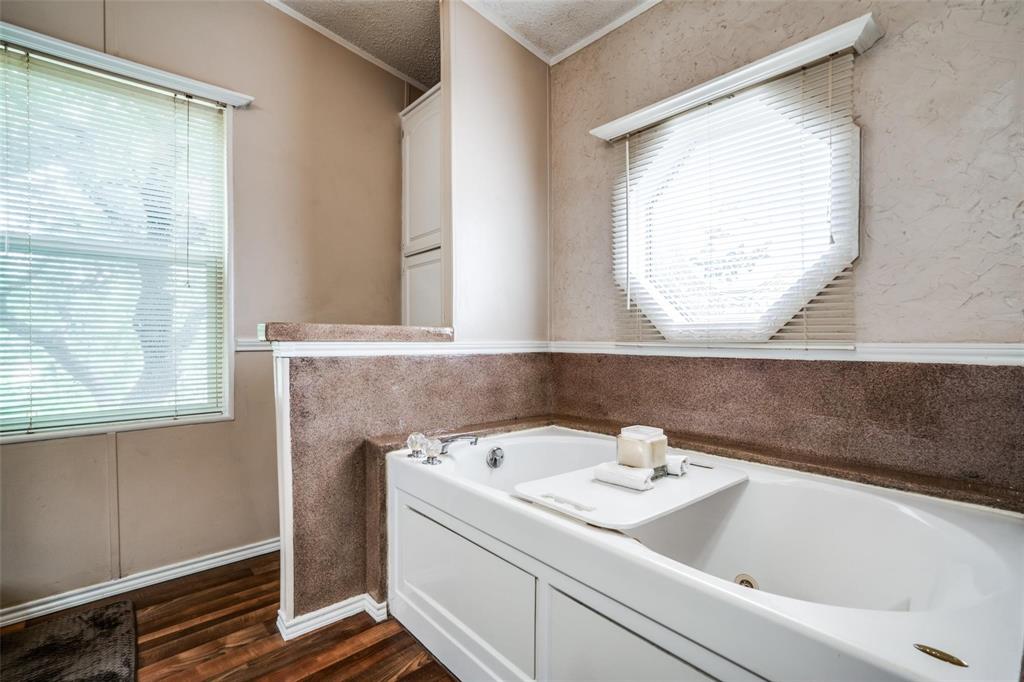 9455 Tranquil Acres Road Fort Worth, TX 76179 - Photo 17 of 20 Jetted soaking tub with an octagonal window, paneled wood-finish flooring, and built-in cabinetry