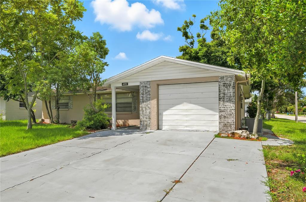 11241 Snyder Avenue Port Richey, FL 34668 - Photo 2 of 24 a front view of a house with a garden and trees