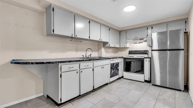 a kitchen with granite countertop a sink a stove and cabinets