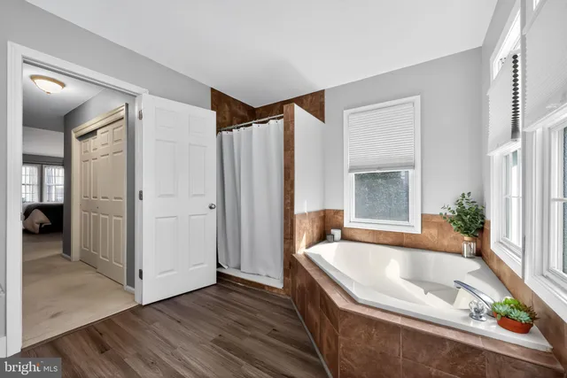 a bathroom with a tub a mirror and a shower