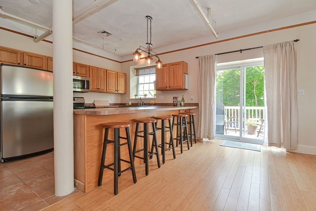 200 Cato Street, Unit 7 Woonsocket, RI 02895 - Photo 7 of 39 a kitchen with stainless steel appliances granite countertop a refrigerator a sink dishwasher a stove and a dining table with wooden floor