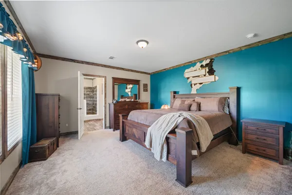 a spacious bedroom with a bed a dresser next to a window