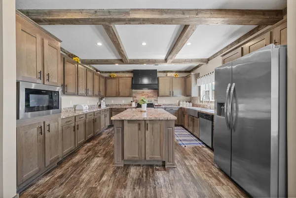 a kitchen with stainless steel appliances granite countertop a refrigerator a sink dishwasher a stove and white countertops with wooden floor