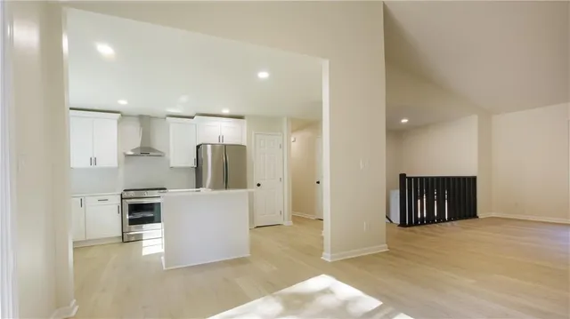 a kitchen with kitchen island a refrigerator and a stove top oven