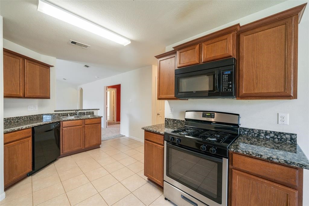 9926 Opal Rock Drive Rosharon, TX 77583 - Photo 5 of 8 a kitchen with granite countertop a stove top oven microwave and cabinets