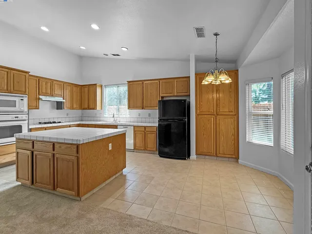 a kitchen with stainless steel appliances granite countertop a stove a sink a refrigerator and a granite counter tops