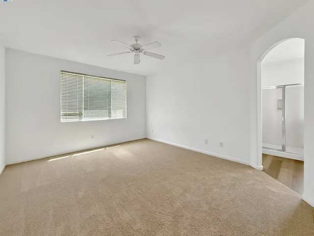 an empty room with a chandelier fan and windows