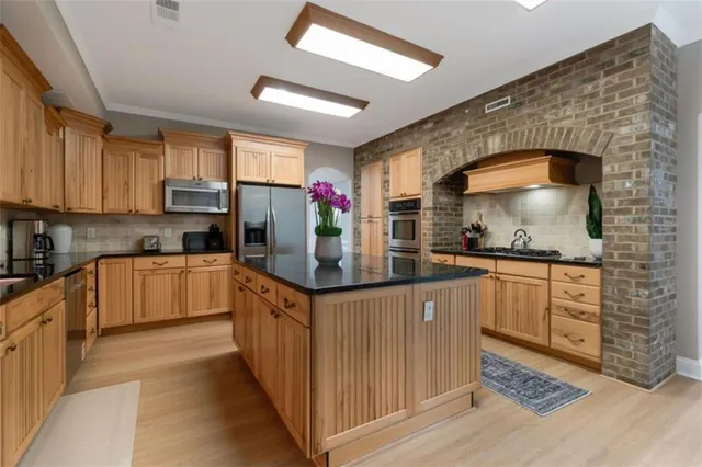 a kitchen with stainless steel appliances kitchen island granite countertop a stove a sink and a refrigerator