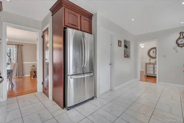 a view of a refrigerator in kitchen and an empty room