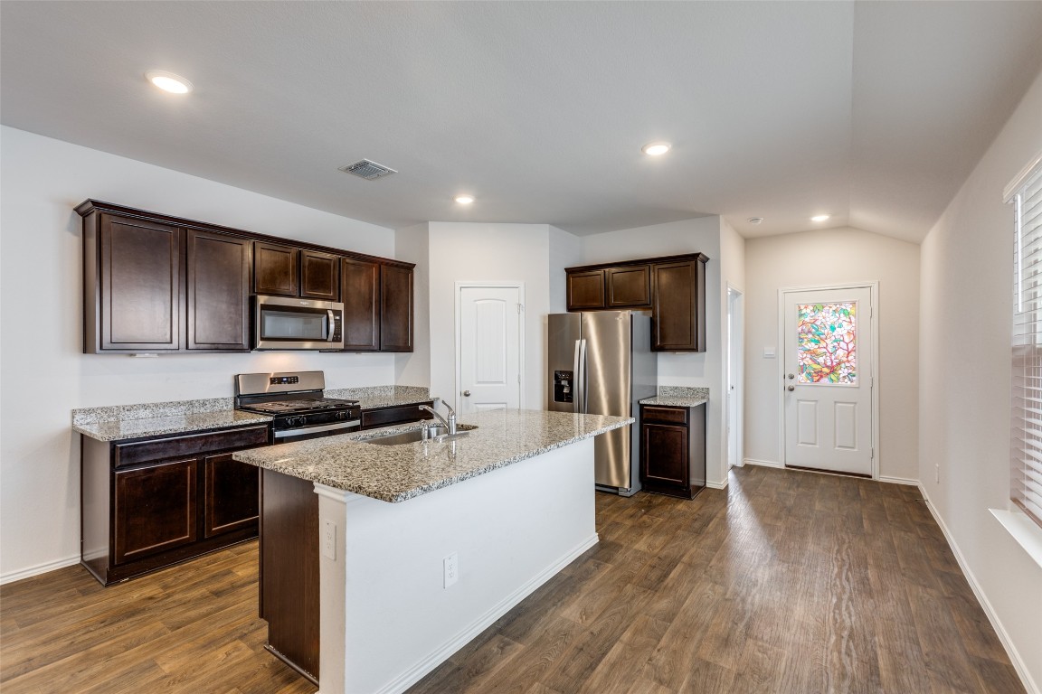 408 Frogmore Loop Kyle, TX 78640 - Photo 7 of 25 a large kitchen with a center island stainless steel appliances cabinets and wooden floor