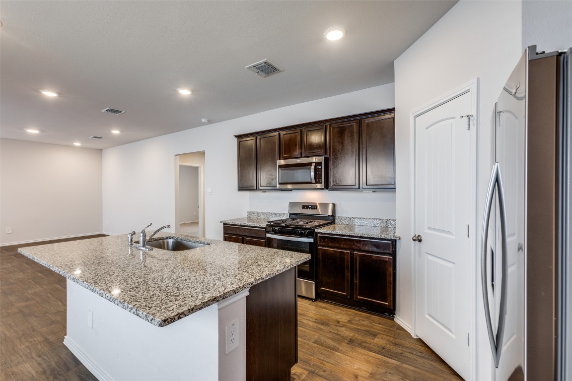 408 Frogmore Loop Kyle, TX 78640 - Photo 9 of 25 a kitchen with stainless steel appliances granite countertop a sink stove and refrigerator