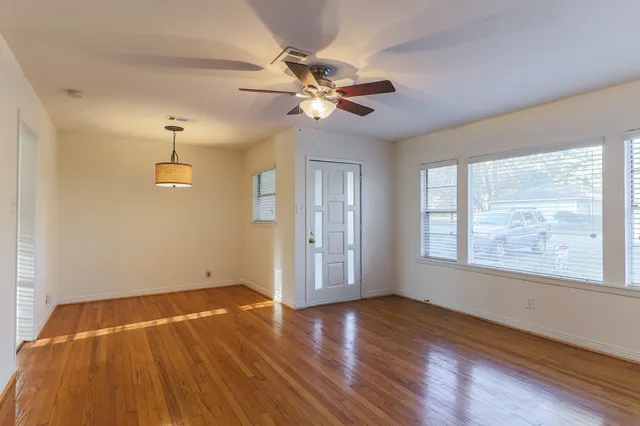 a view of an empty room with wooden floor and a window
