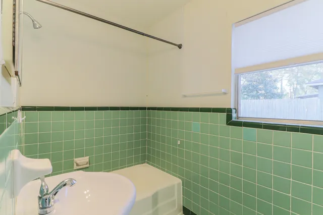 a bathroom with a blue tub shower and a window