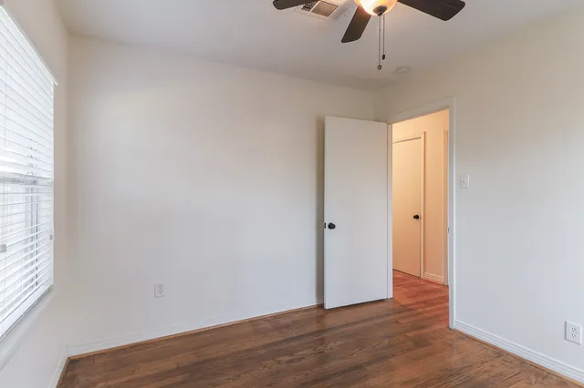 a view of an empty room with wooden floor chandelier fan