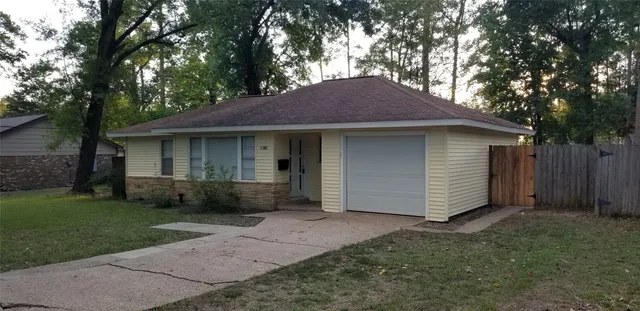 a view of a house with a yard plants and large tree