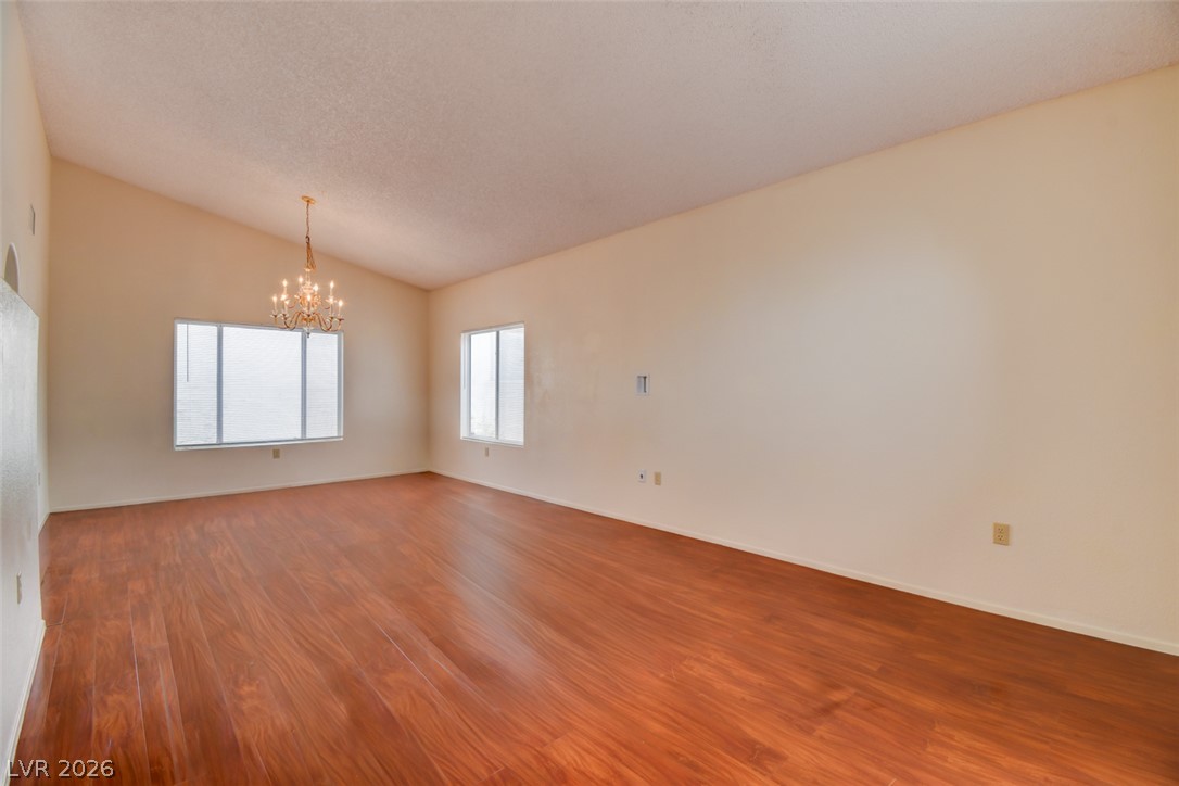 5 Tarryall Terrace Henderson, NV 89074 - Photo 7 of 44 A spacious room offers vaulted ceilings, warm hardwood floors, and a bright chandelier.