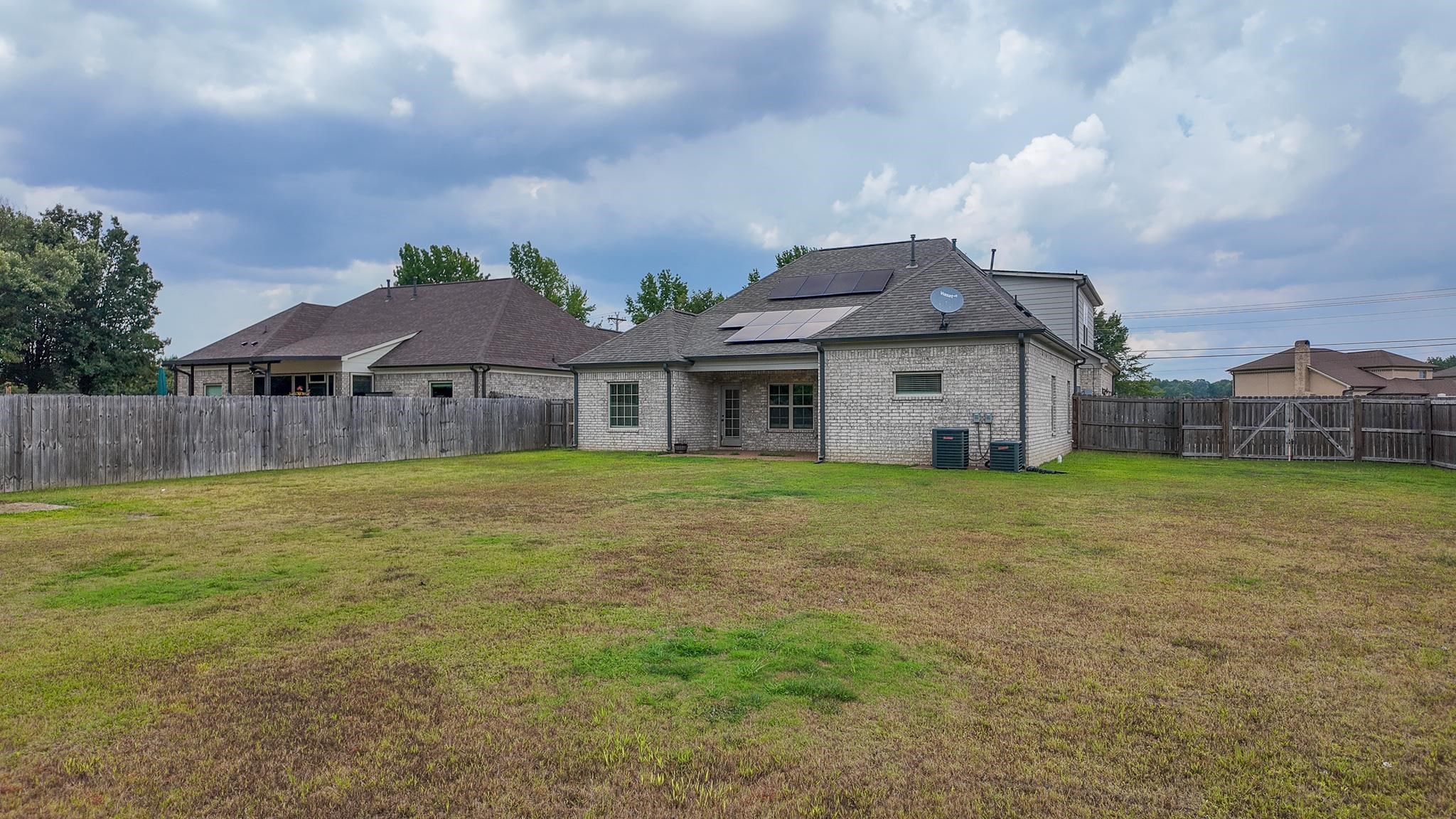 5217 Nail Road Olive Branch, MS 38654 - Photo 29 of 35 Rear view of house with a fenced backyard, solar panels, brick siding, a patio area, and roof with shingles