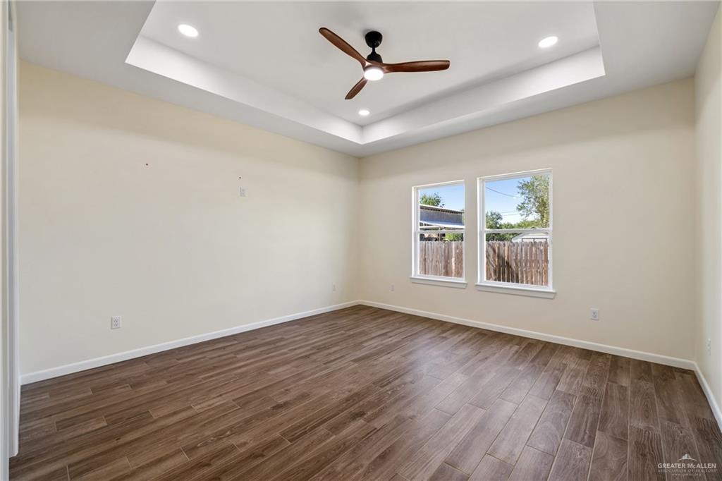 1602 Helen Drive Weslaco, TX 78596 - Photo 20 of 32 an empty room with wooden floor ceiling fan and windows