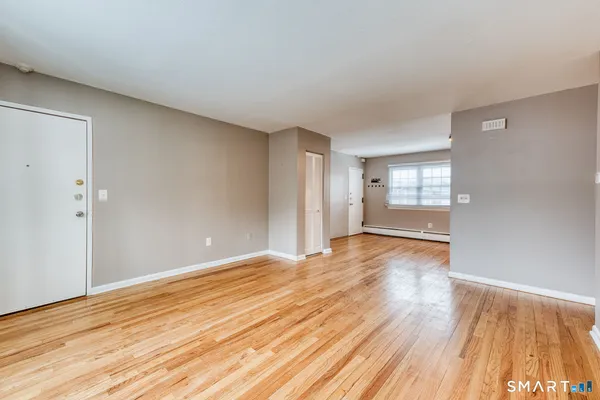 a view of an empty room with wooden floor and windows