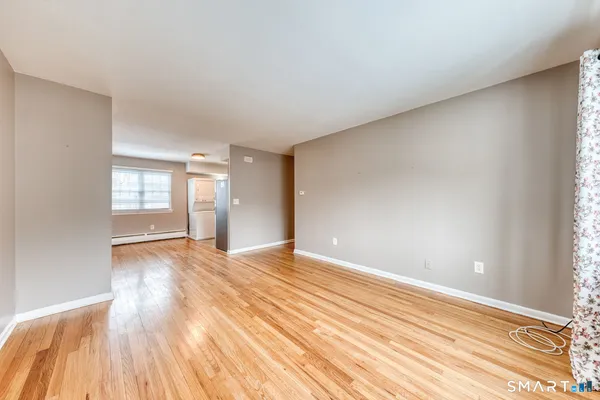 a view of an empty room and window and wooden floor