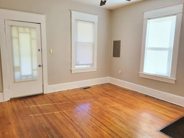 an empty room with wooden floor and windows