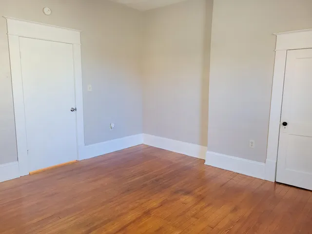 a view of a room with wooden floor fan and windows
