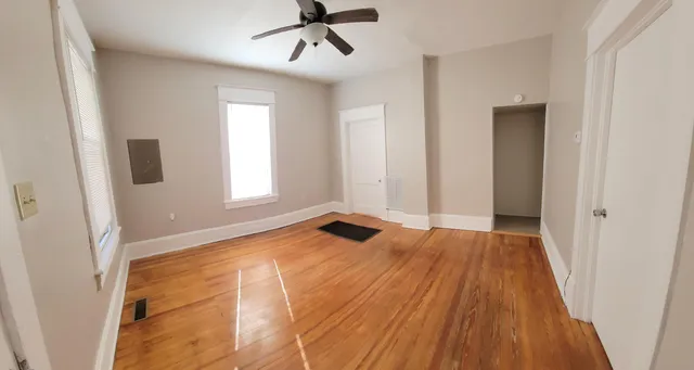 a view of an empty room with wooden floor and a window