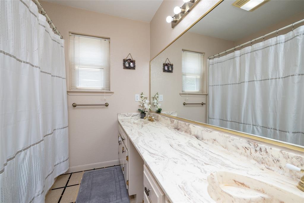 151 County Road 3699 Springtown, TX 76082 - Photo 14 of 35 Bathroom vanity featuring an integrated sink, expansive countertop, full-width mirror, and a linear light fixture