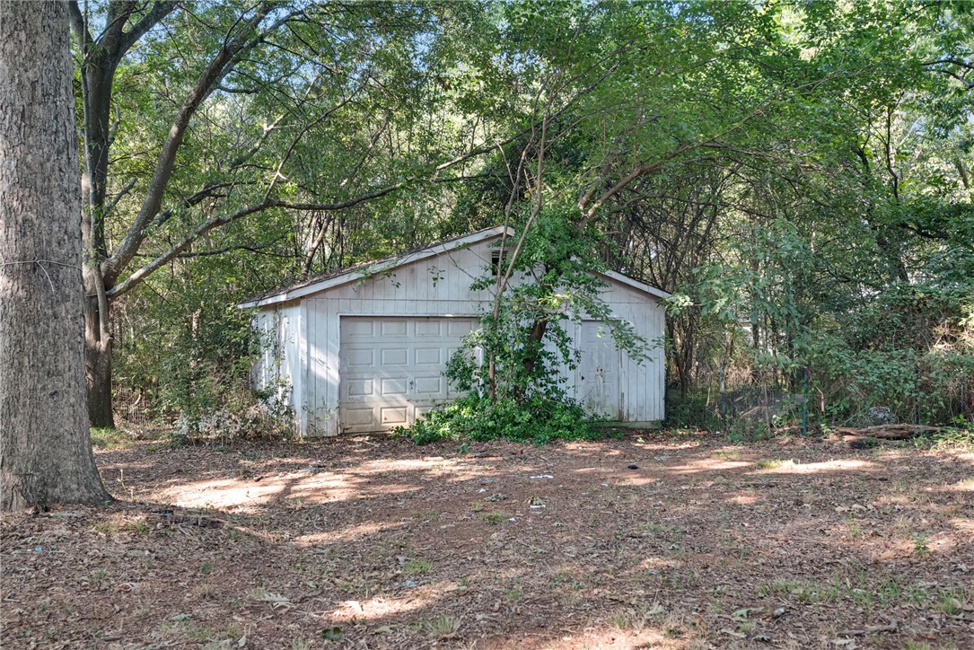 403 Lewis Street Anderson, SC 29624 - Photo 19 of 35 A detached outbuilding nestled among mature trees offers versatile storage or workshop potential.