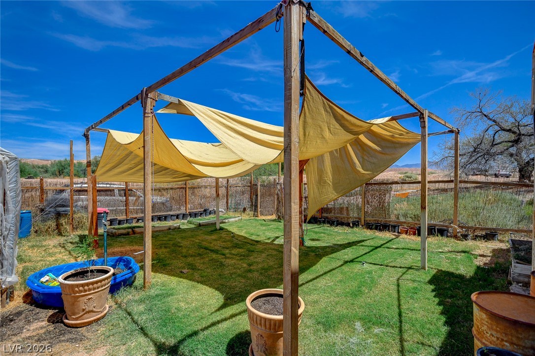 1920 Bowman Road Logandale, NV 89021 - Photo 59 of 68 Shade sails stretch over a grassy yard enclosed by fencing under open blue skies.