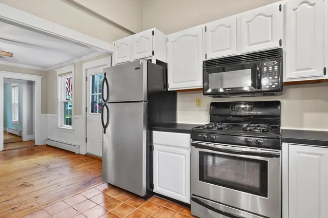 a kitchen with stainless steel appliances white cabinets a stove a microwave and a refrigerator