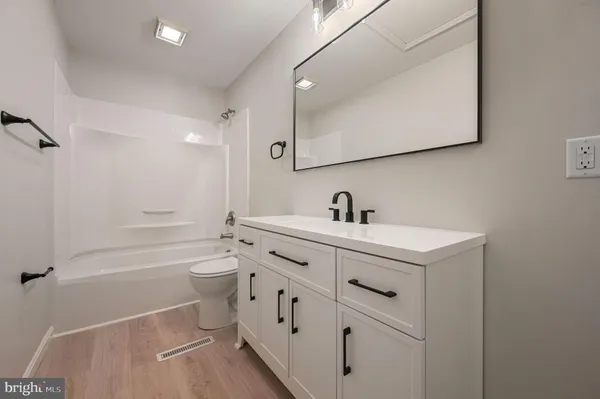 a bathroom with a toilet a sink a mirror a bathtub and vanity