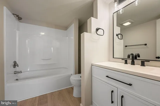a bathroom with a bathtub shower sink vanity and toilet